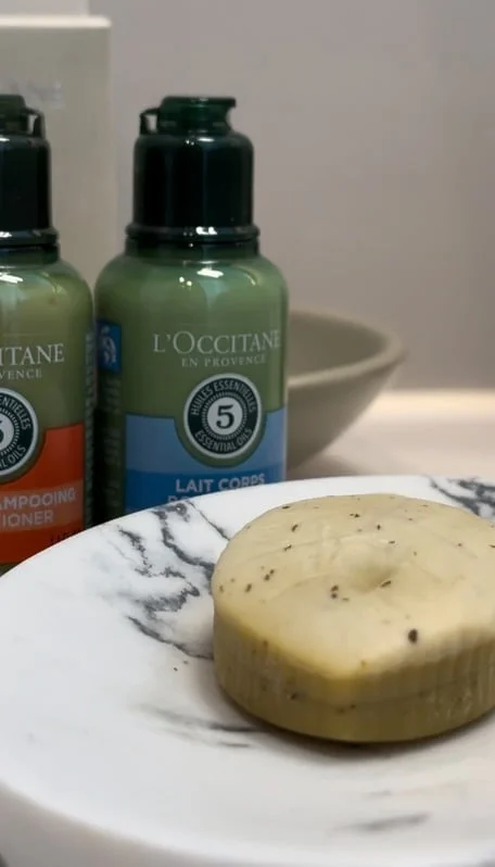 L'Occitane beauty products arranged on a marble bathroom surface