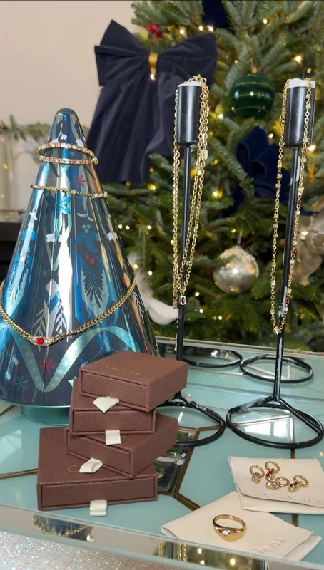 Gold jewellery displayed with gift boxes beside a Christmas tree